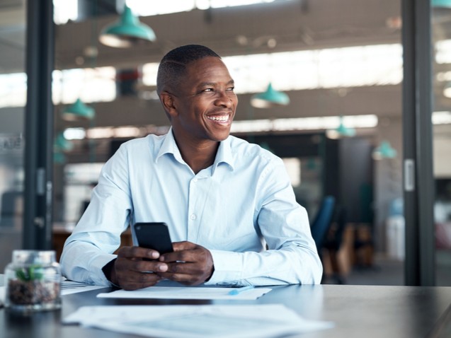 Smiling professional man working on his phone in an office