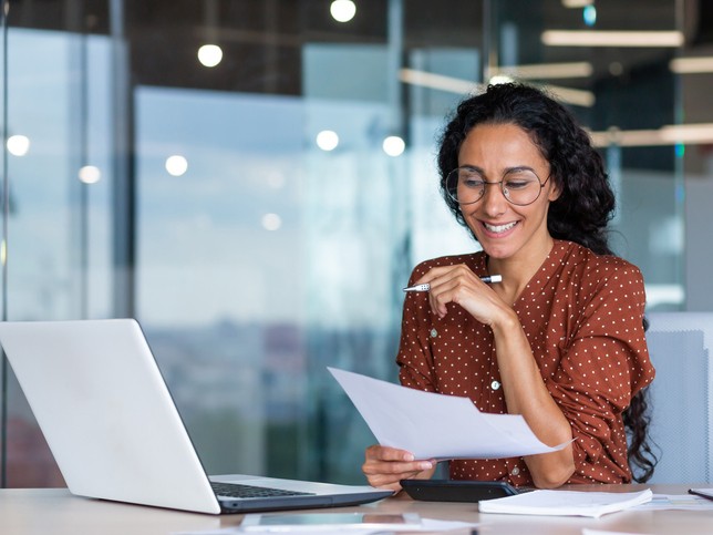 Woman with a pen and laptop doing research on errors and omissions insurance