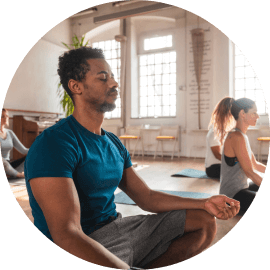Yoga instructor leading a group of people mediating in yoga class 