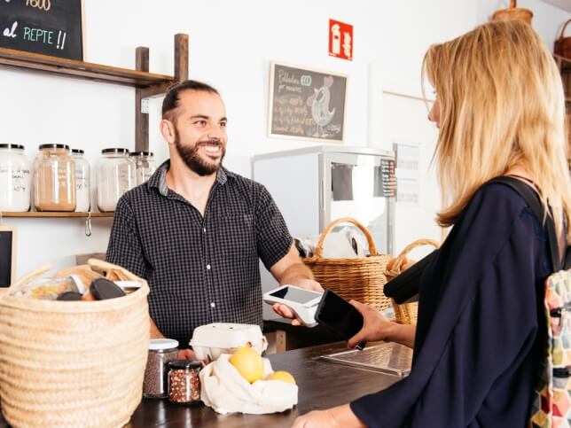 Business owner working with a paying customer at checkout counter 