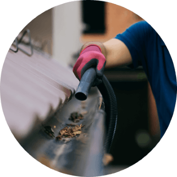 Exterior cleaning professional using leaf blower to clear gutters 