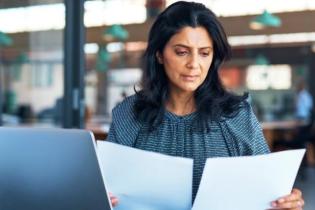 Professional woman reviewing papers for professional liability insurance | Who needs insurance for professional liability