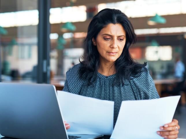 Professional woman reviewing papers for professional liability insurance | Who needs insurance for professional liability