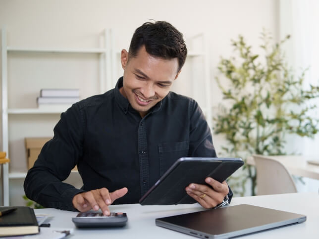 smiling business owner calculating | small business insurance cost on calculator | How Much Does $1 Million General Liability Insurance Cost?