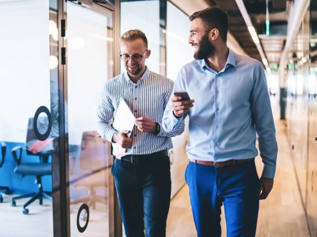 Two professional men walking together in an office hallway