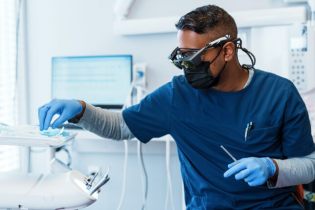 Dentist wearing mask working with tools in dental office | dental malpractice insurance tail coverage