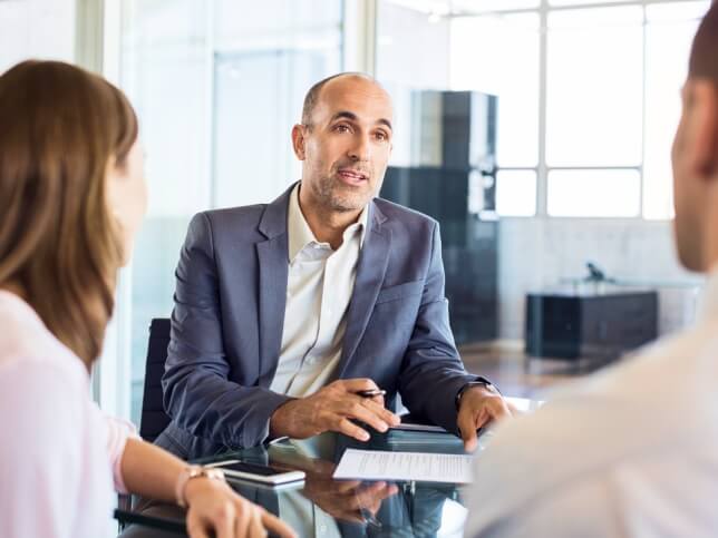 insurance agent working with clients in office | Guide to e&o insurance for insurance agents