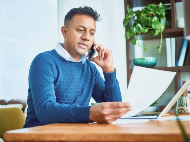 male professional at desk talking on cellphone about insurance