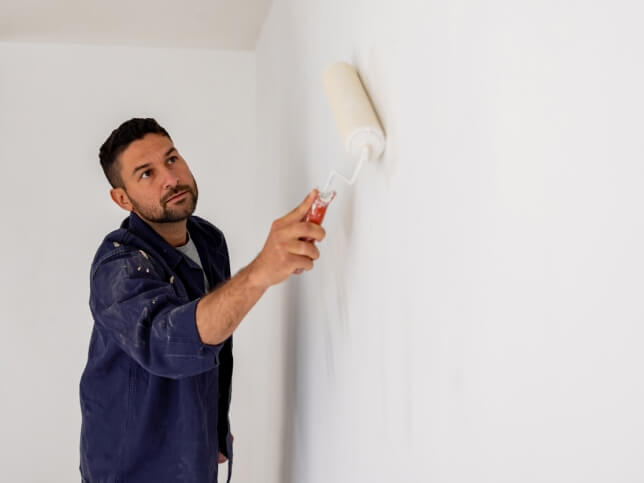 professional interior painter using a roller to paint a wall