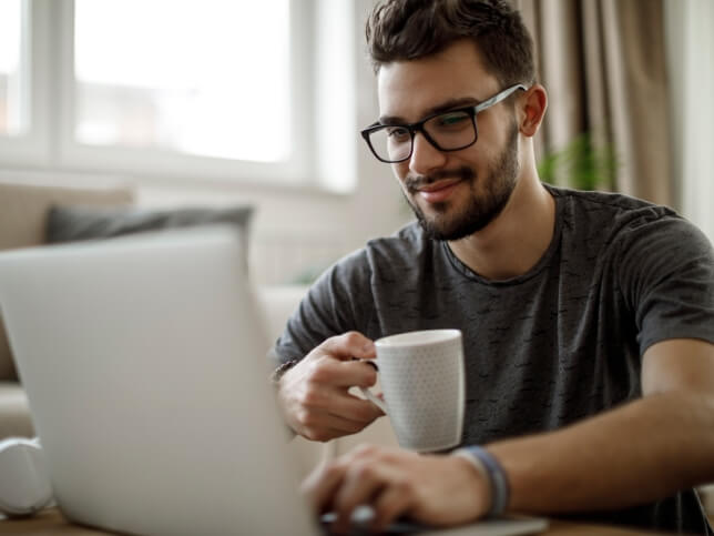 small business owner with coffee searching for insurance on laptop