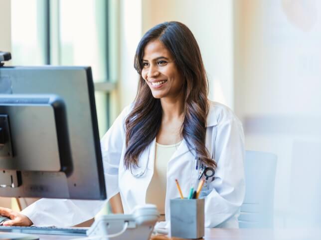 smiling dentist on computer researching dental malpractice insurance