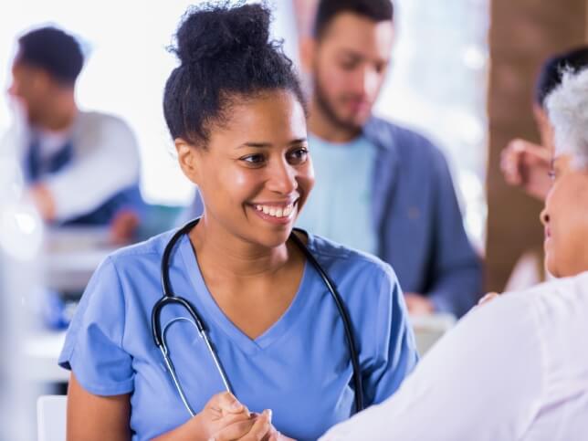 smiling female nurse talking to patient in medical facility