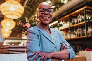 smiling business owner standing arms crossed in her restaurant business liability insurance guide | business liability insurance coverage guide