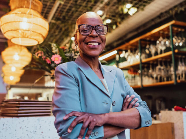 smiling business owner standing arms crossed in her restaurant business liability insurance guide | business liability insurance coverage guide