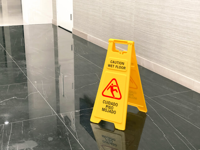 Shiny black marble floor with yellow wet floor sign