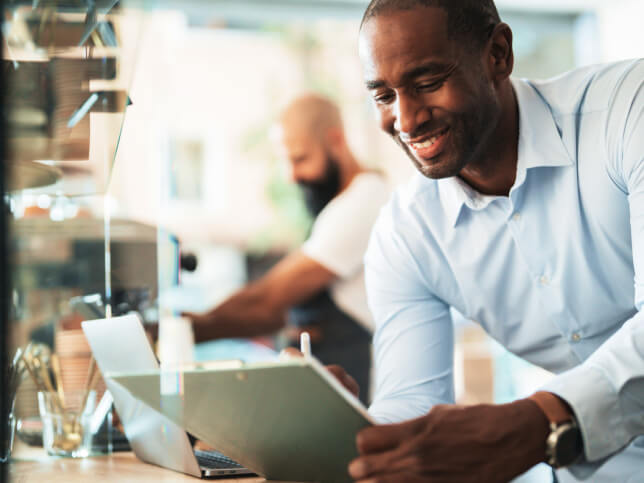 man in a small business looking at a notebook containing general liability insurance FAQs