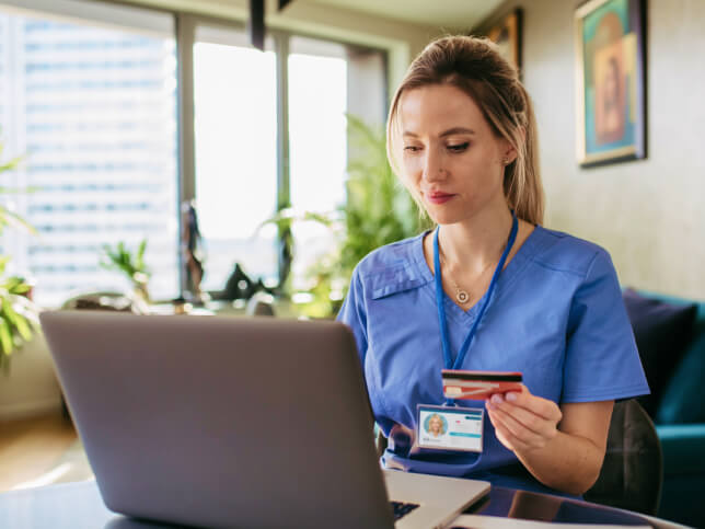 Medical professional in scrubs at computer learning about medical malpractice insurance