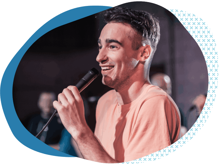stand up comedian in orange shirt telling joke in microphone about entertainer liability insurance